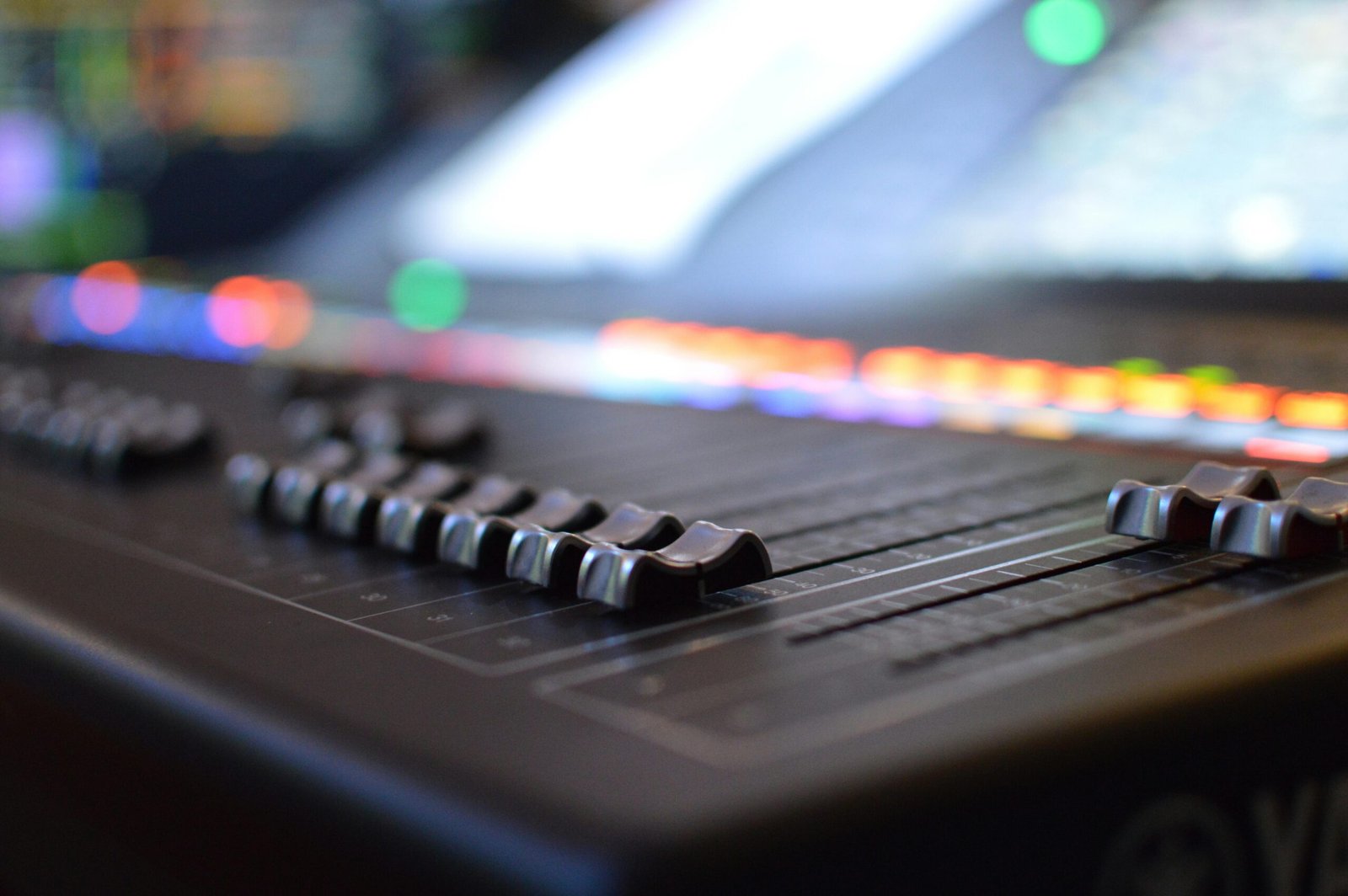 A detailed view of an audio mixer panel with glowing LED lights in a studio setting.